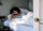 Person resting on a white bed in a small, softly lit room, wrapped in white bedding and surrounded by minimal, calming decor.