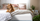 Brown dog resting on a bed with a Zinus memory foam mattress, beige blanket, and gray textured throw in a cozy bedroom with blush bedding, plants, and soft morning light through white curtains
