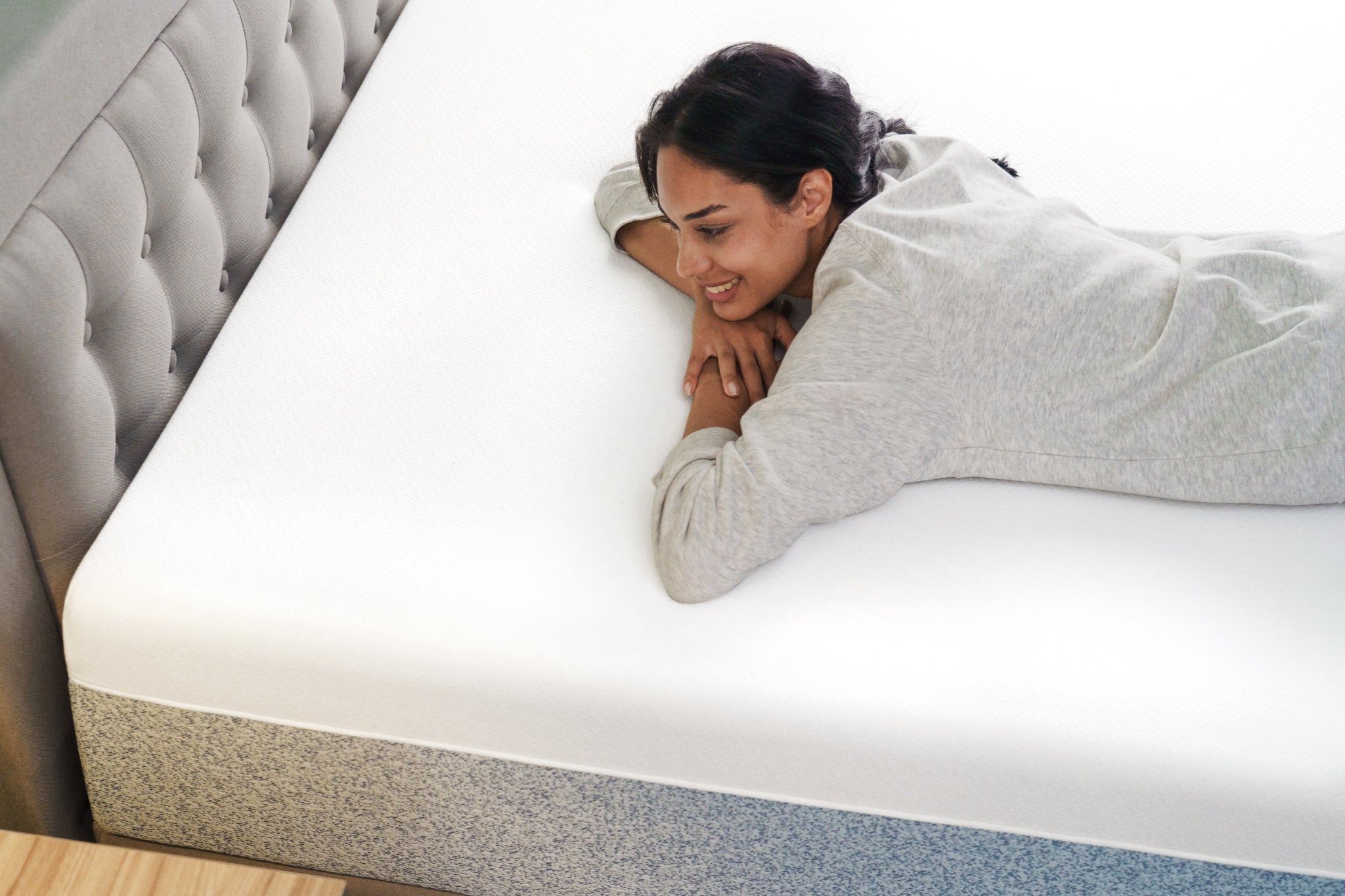 Woman laying comfortably on the Zinus Ultra Cooling Green Tea Hybrid Mattress with a tufted bed frame, demonstrating smooth surface, supportive foam, and breathable comfort.