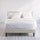 Zinus Shalini Upholstered Platform Bed Frame styled with white bedding in a minimal bedroom. The diamond-stitched headboard in dark gray fabric adds sophistication, while durable slats provide strong mattress support without the need for a box spring