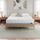 Zinus Balanced Comfort Core Memory Foam Mattress fully set up on a natural wood platform bed frame in a light, airy bedroom with white and green pillows, nightstands, and lamps on either side, showing the mattress in its intended home bedroom setting.