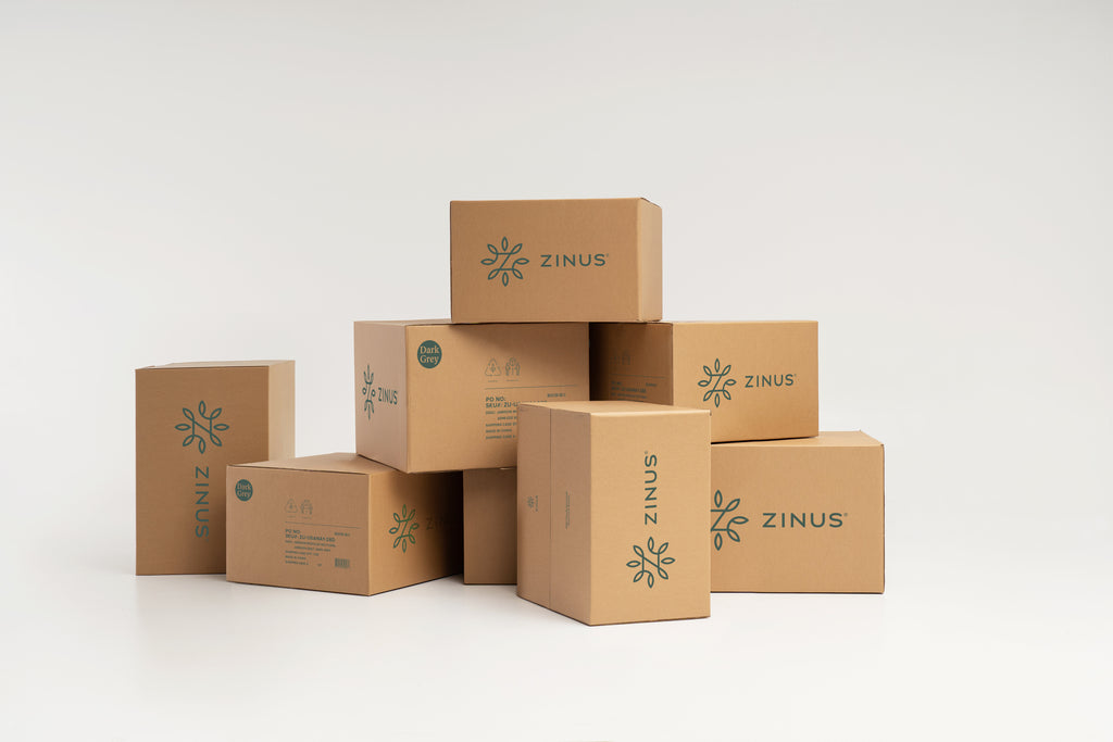 Stack of Zinus delivery boxes in various sizes, each printed with the Zinus logo and labeled Dark Grey, shown on a plain white background, highlighting compact shipping for easy setup 