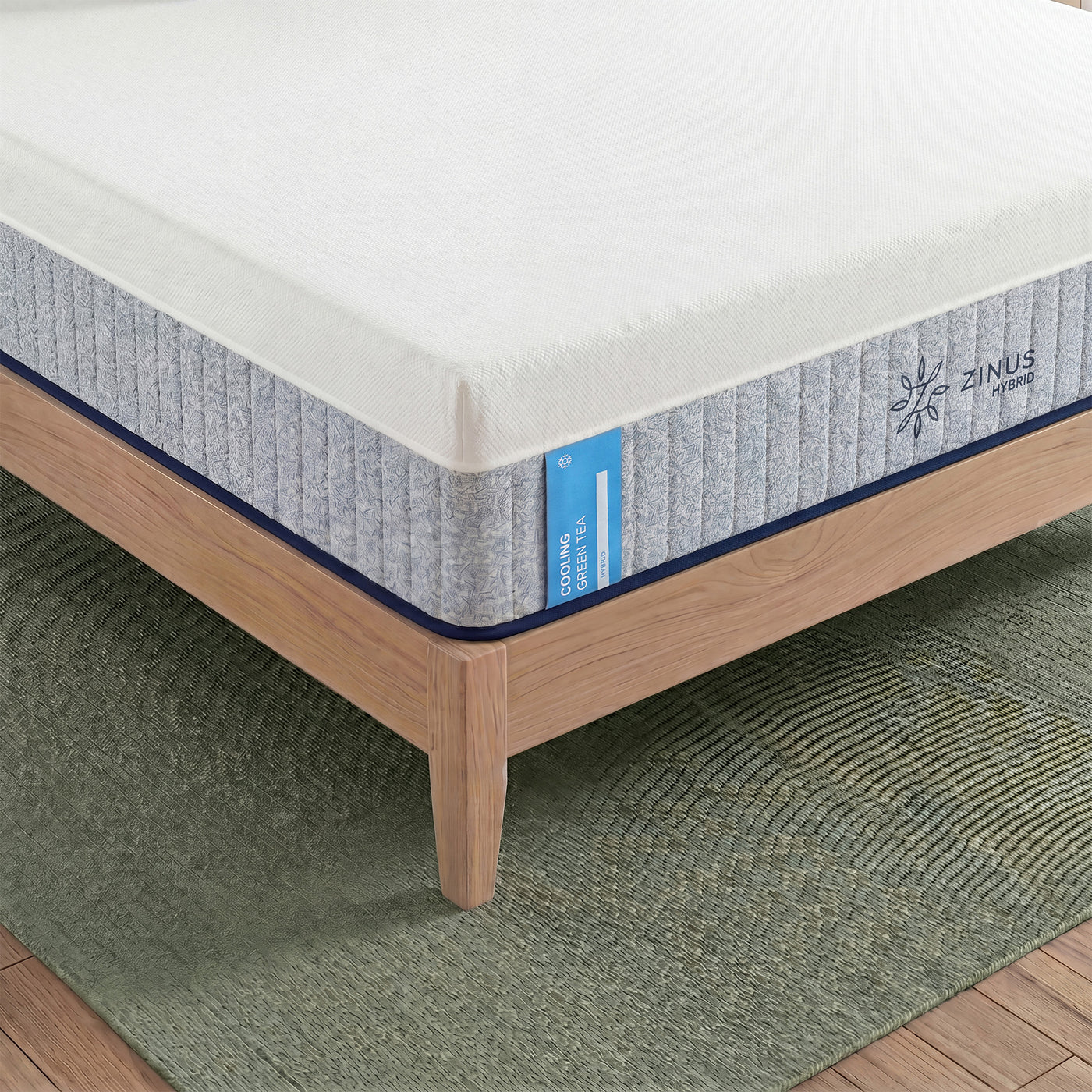 Zinus Cooling Green Tea Hybrid Mattress, Queen, close-up corner detail on wood platform bed frame showing ribbed white and gray cover, label text reading cooling green tea hybrid, and Zinus Hybrid logo.