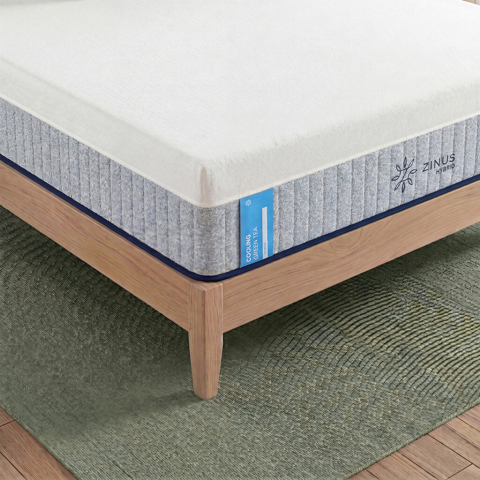 Zinus Cooling Green Tea Hybrid Mattress, Queen, close-up corner detail on wood platform bed frame showing ribbed white and gray cover, label text reading cooling green tea hybrid, and Zinus Hybrid logo.