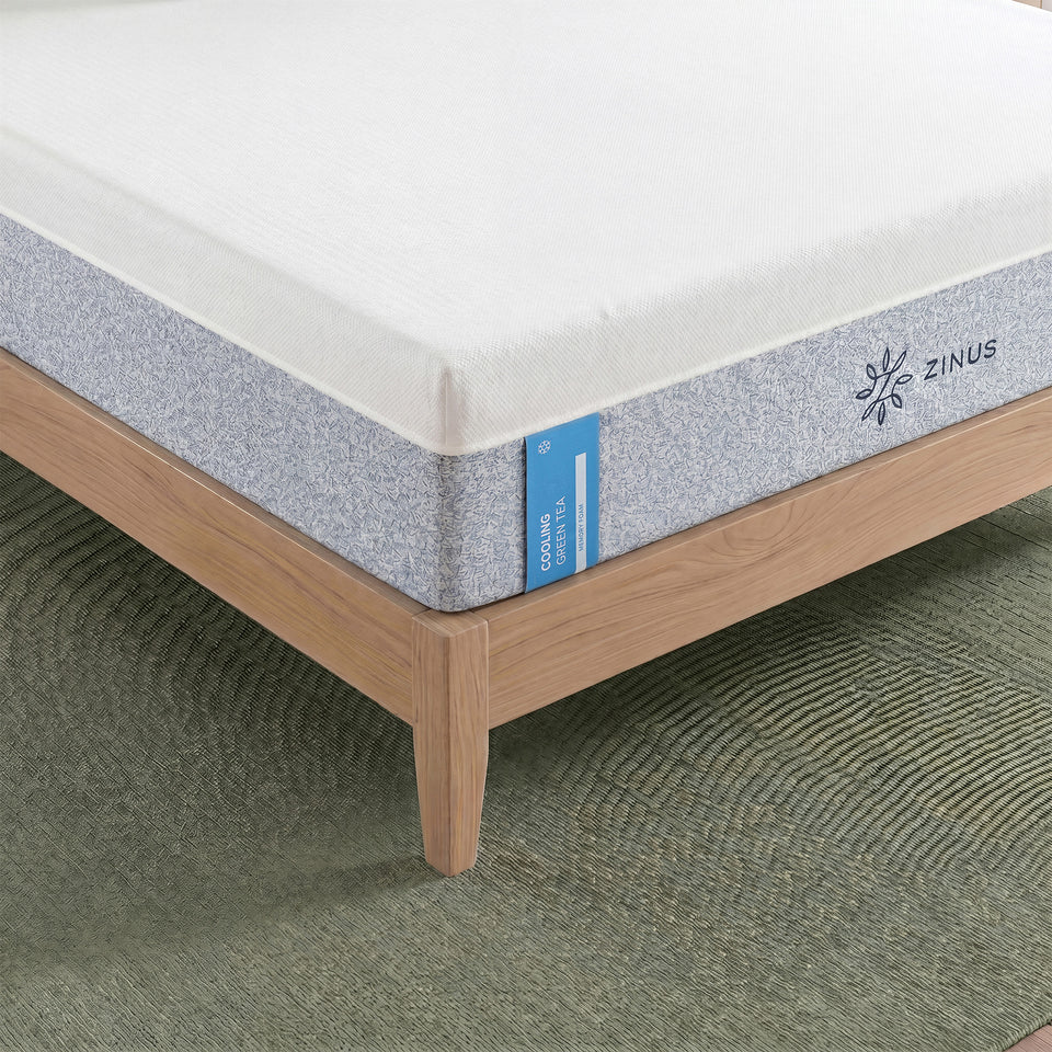 Zinus Cooling Green Tea Memory Foam Mattress, Queen, close-up corner detail on wood platform bed frame showing white cover, gray textured side panel, label text reading cooling green tea memory foam, and Zinus logo.