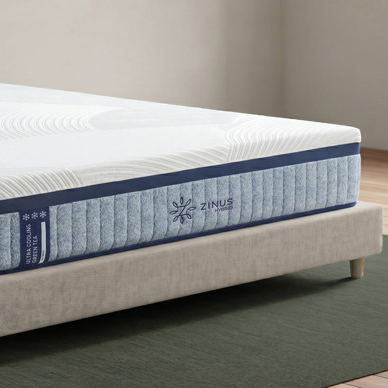 Zinus Ultra Cooling Green Tea Hybrid Mattress, Queen, close-up corner detail on upholstered bed frame showing quilted white cover, ribbed blue side panel, snowflake icons, and Zinus Hybrid logo.