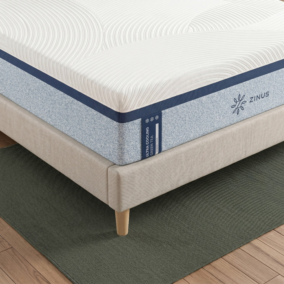 Zinus Ultra Cooling Green Tea Memory Foam Mattress, Queen, close-up corner detail on upholstered bed frame showing quilted white cover, blue textured side panel, snowflake icons, and Zinus logo.