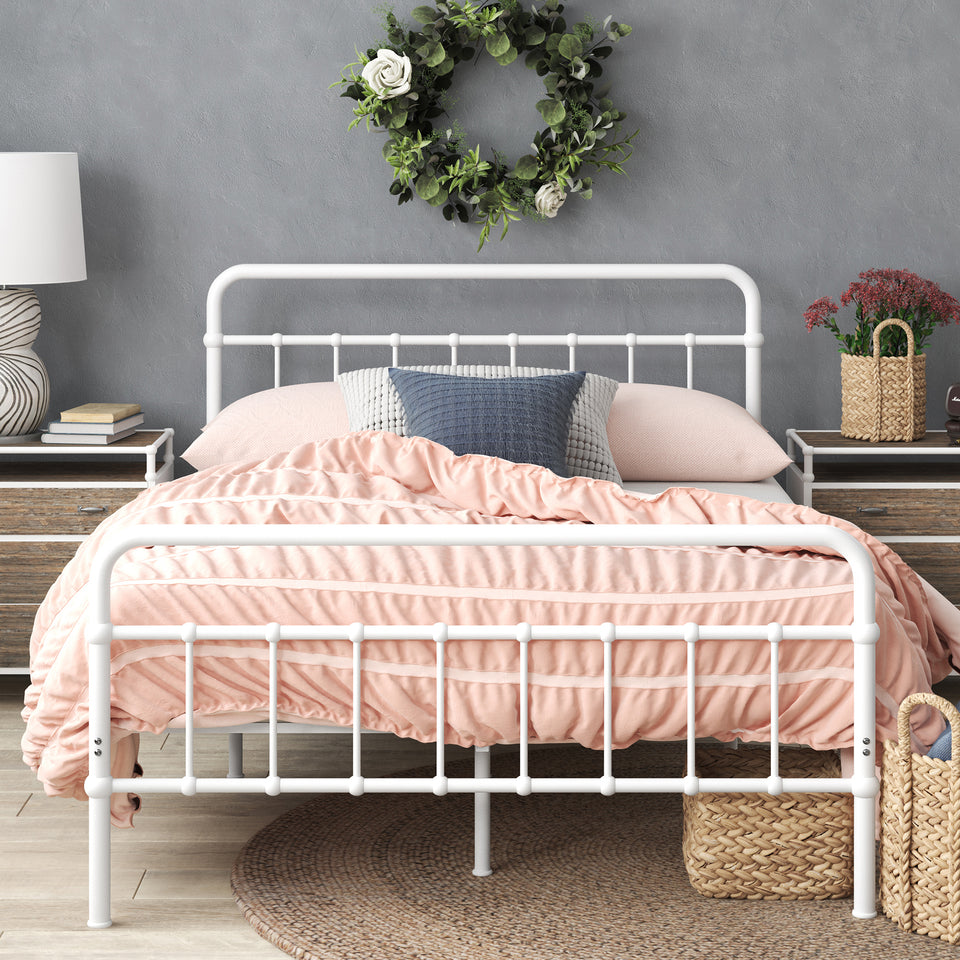 Styled bedroom featuring Zinus metal bed frame with headboard, dressed in pink bedding with decorative pillows and wicker storage basket beneath. Sturdy steel frame adds modern farmhouse charm while supporting queen or full mattresses with underbed storage space.