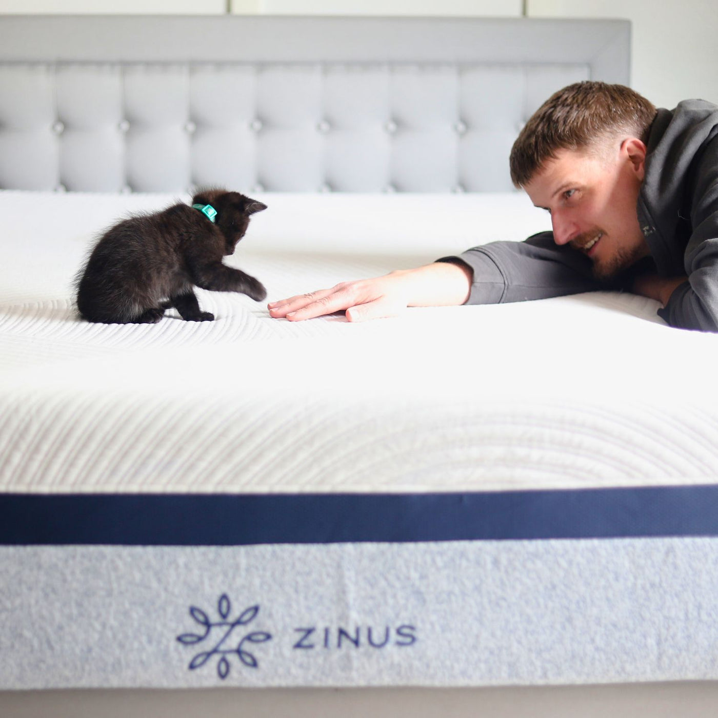  man and a small black kitten playing on a Zinus Ultra Cooling Green Tea Memory Foam Mattress, designed with cooling gel and pressure relief for a comfortable sleep experience.