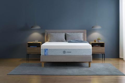 Zinus Cooling mattress with breathable cover on upholstered platform bed with gray headboard, styled in modern bedroom with wooden nightstand, gray bedding, and pendant light.