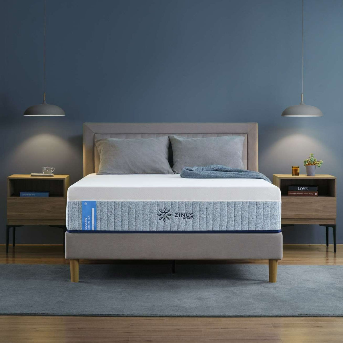 Zinus Cooling Green Tea Hybrid Mattress shown in a modern bedroom with upholstered bed frame. Hybrid mattress blends cooling gel memory foam, green tea infusion, and durable springs to provide refreshing comfort, support, and lasting freshness for restful sleep.