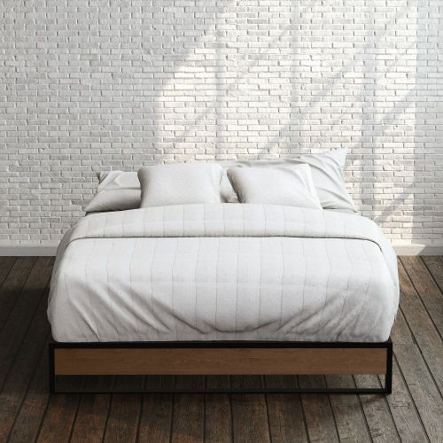 Zinus Suzanne Metal and Bamboo Platform Bed Frame in queen size, styled with white bedding against a brick wall backdrop. Black steel frame with bamboo accent panel and slatted base offers sturdy support and a clean, modern look for any bedroom.