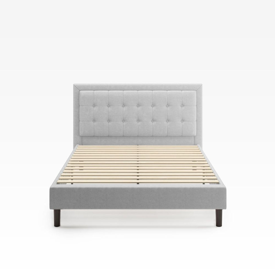 Zinus Dachelle Upholstered Platform Bed Frame in light gray featured in a classic bedroom with wood furniture and modern rug. Square tufted headboard and sturdy platform frame combine durability and elegance for timeless bedroom style