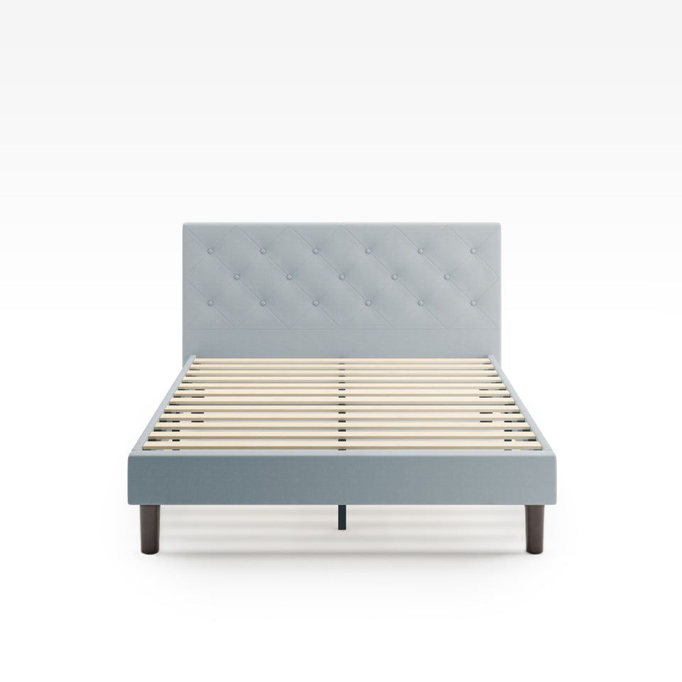 Zinus Shalini Upholstered Platform Bed Frame in a light grey finish, shown from the front without a mattress. Features a button-tufted headboard, wooden slats for strong mattress support, and a modern upholstered design that fits any bedroom style