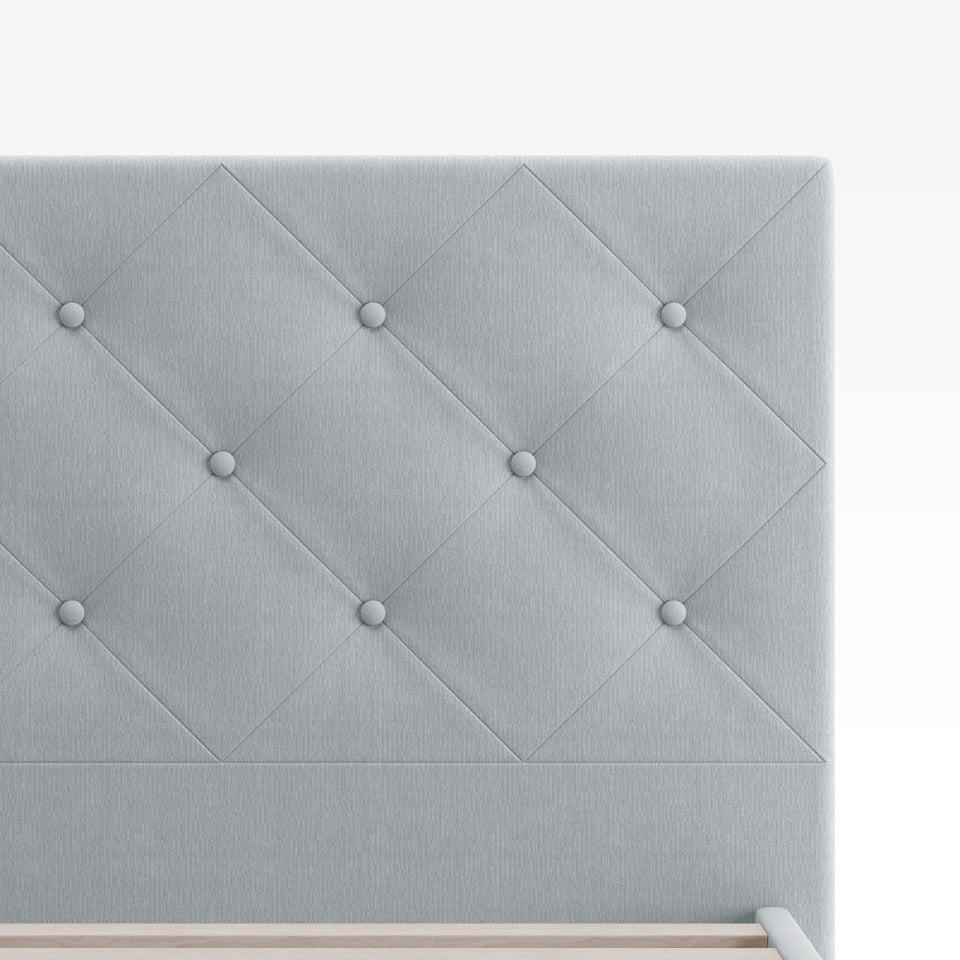 Close-up of Zinus Shalini Upholstered Platform Bed Frame headboard in light gray fabric. The diamond-stitched, button-tufted design adds a touch of elegance and texture, enhancing bedroom décor while offering durable comfort and long-lasting style