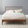 Zinus Linda Wood Platform Bed Frame shown styled with white bedding against a gray wall. Rich walnut wood frame and tall slatted headboard create a warm mid-century centerpiece. Strong wood slats provide sturdy mattress support with lasting comfort and simple modern design